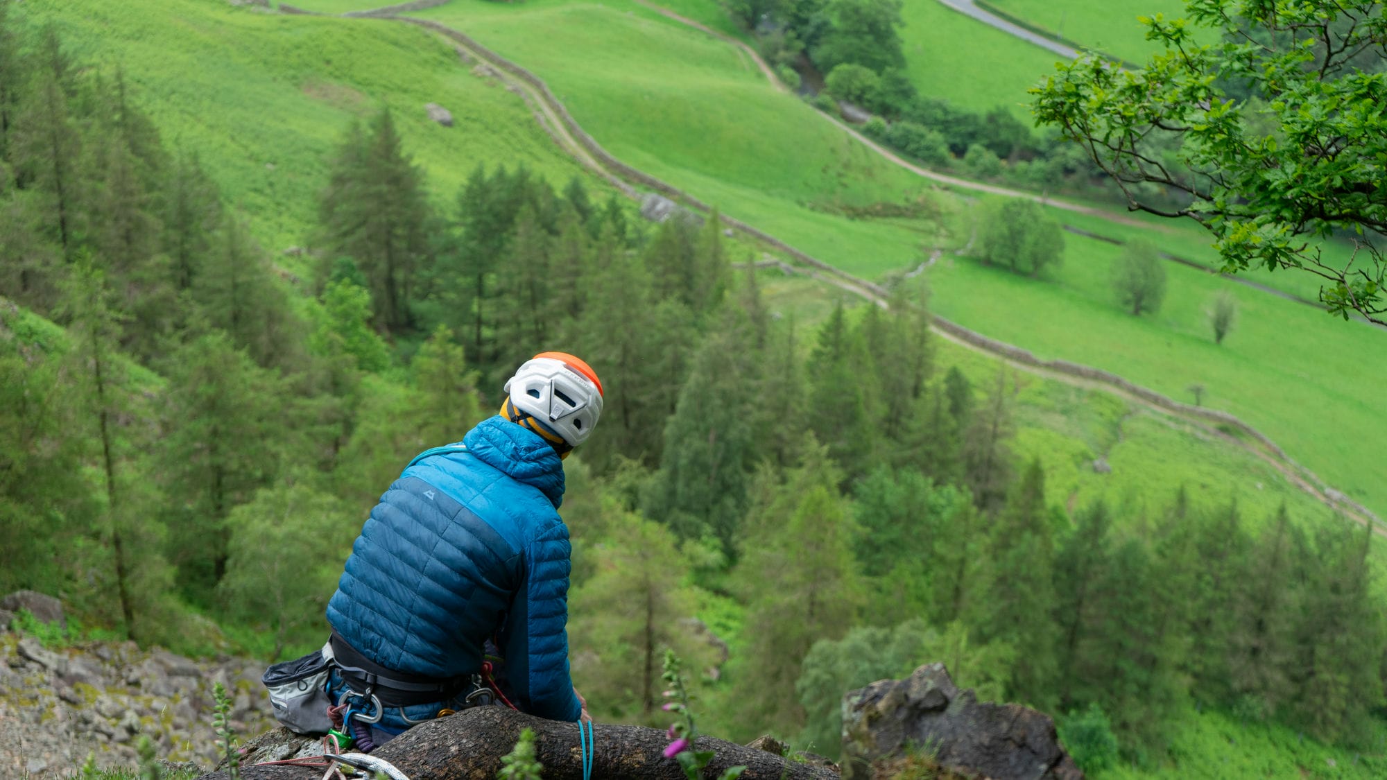 climber sat at the top of crag taking in the views of the lake district in langdale