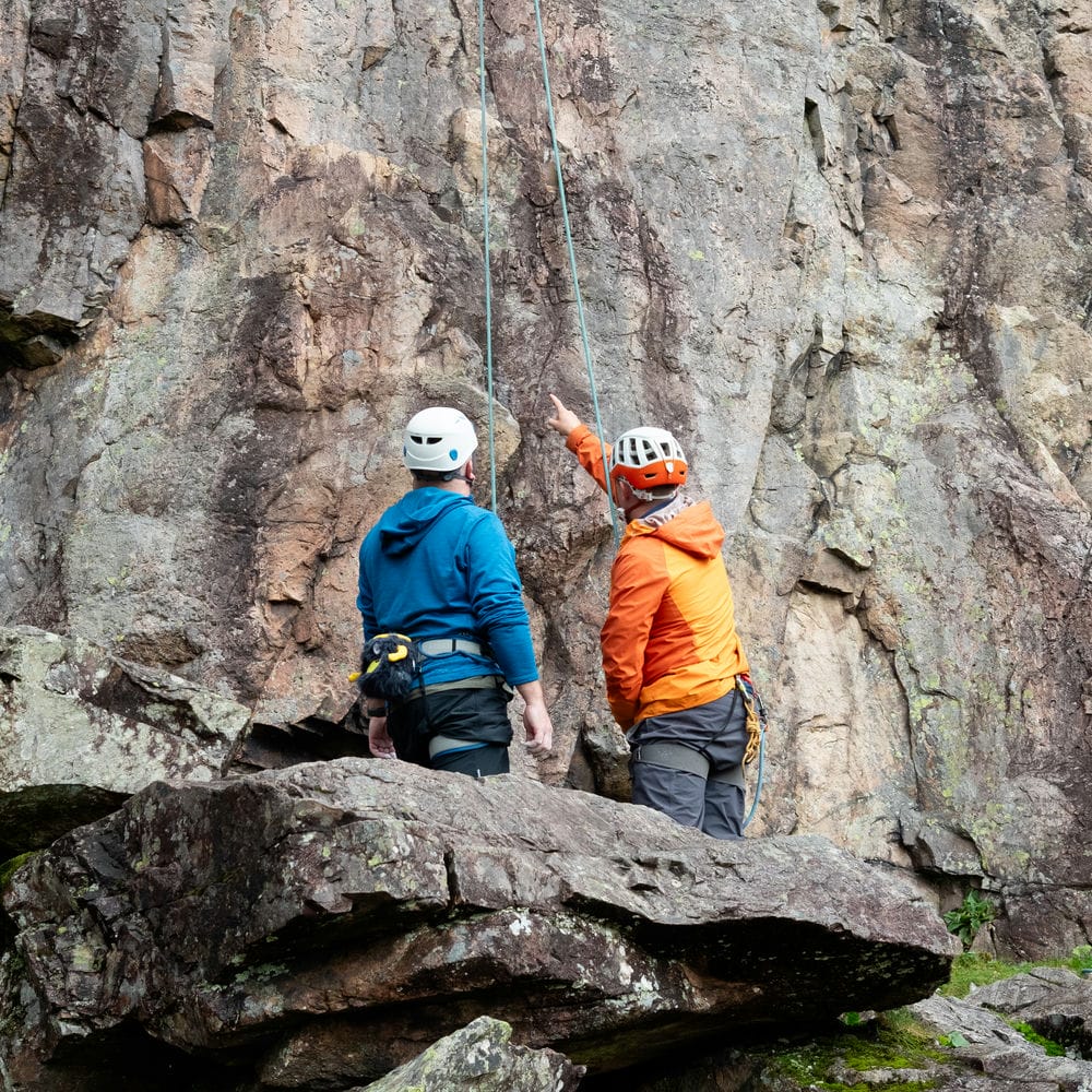 instructor explaining something to a client at the base of a crag
